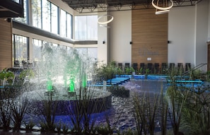A spacious indoor area with a water feature in the center, surrounded by seating and plants.