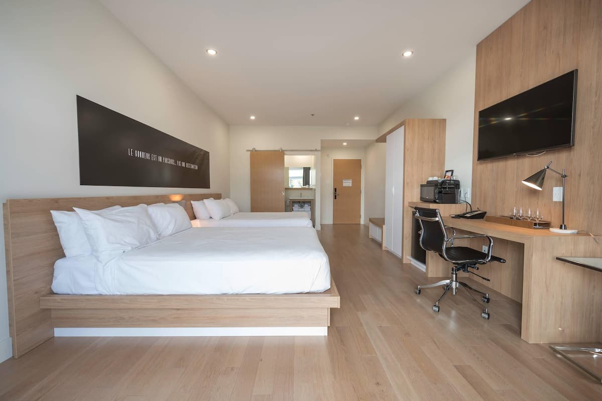 Een moderne hotelkamer met een bed, bureau, stoel, televisie en een groot kunstwerk aan de muur.