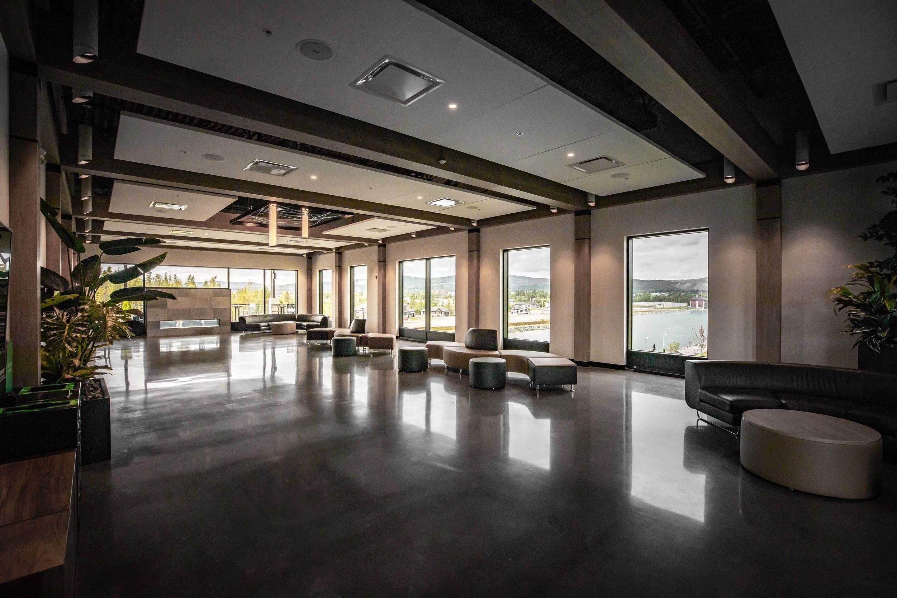 Eine großzügige Lobby mit poliertem Boden, großen Fenstern mit Blick ins Freie und modernen Sitzmöbeln.