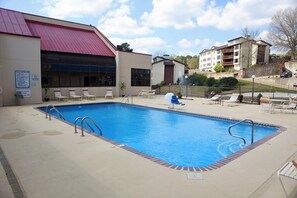 Uma piscina com espreguiçadeiras e um edifício com telhado vermelho.