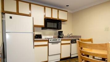 A compact kitchen with white cabinets, a black microwave, a stove, and a dishwasher.