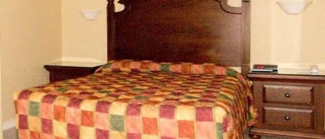 A room with a wooden bed, a nightstand, a lamp, and a painting on the wall.