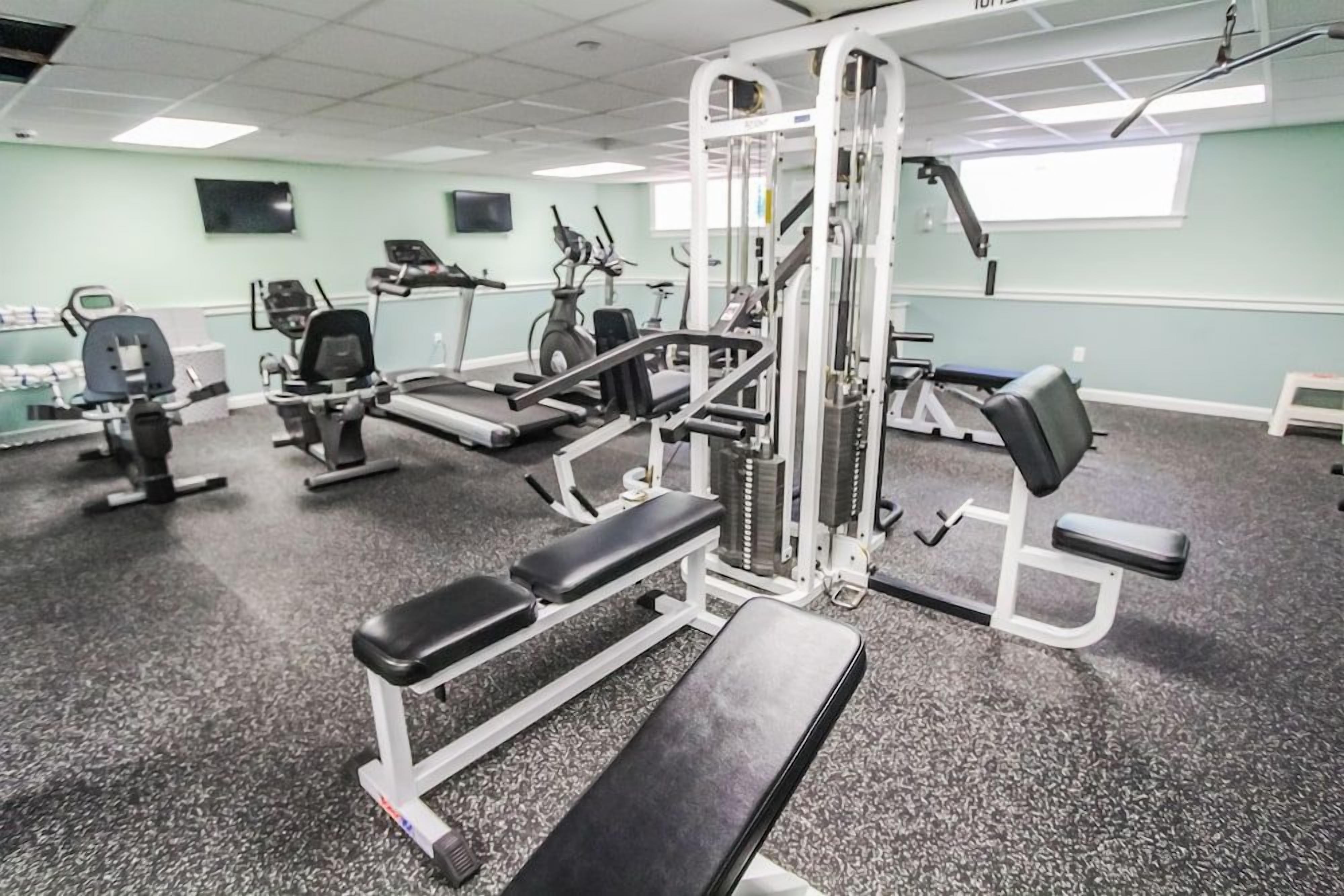 A gym with various exercise equipment, including treadmills, weight machines, and benches.