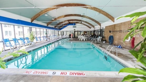 Une piscine intérieure avec des chaises bleues et un panneau indiquant « IL EST INTERDIT DE PLONGER ».