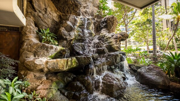 A waterfall feature with a rocky backdrop and surrounding greenery.