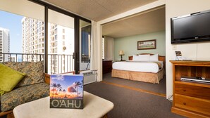 A hotel room with a balcony, a bed, a TV, and a table with a book.