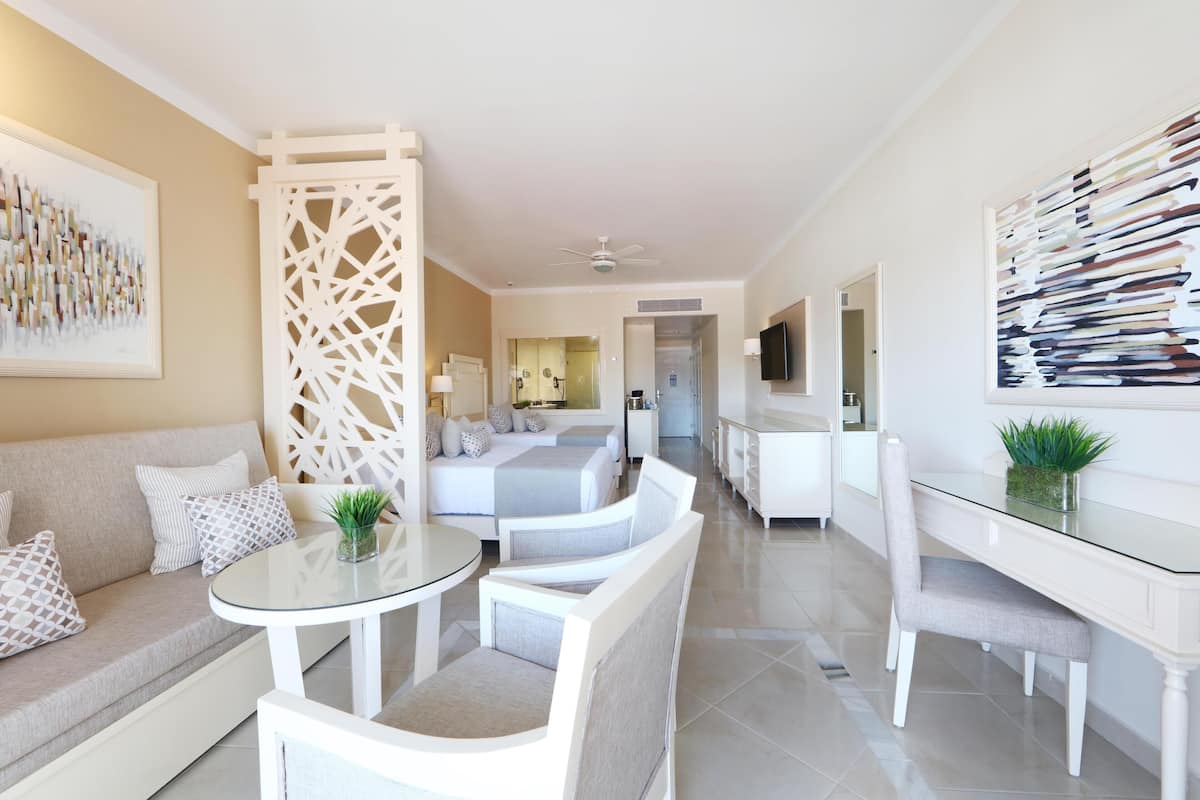 Une chambre d’hôtel moderne équipée d’un canapé, d’une table à manger avec des chaises, d’un lit et d’une télévision.