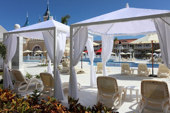 A poolside area with white canopies, lounge chairs, and a pool. - Bahia Principe Explore Legend - Hyatt Inclusive Collection - All Inclusive (Punta Cana)