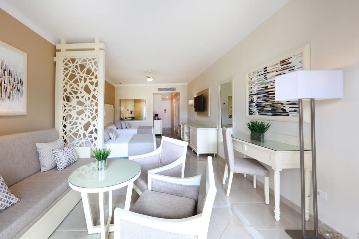 Un salon moderne avec une table basse en verre, des canapés blancs et un coin repas comprenant une table et des chaises en verre.