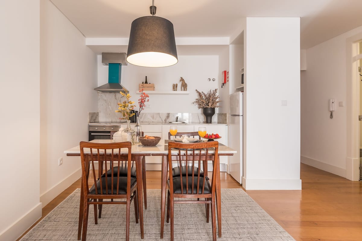 A modern kitchen with white cabinetry, a central island, and a dining area with two wooden chairs.