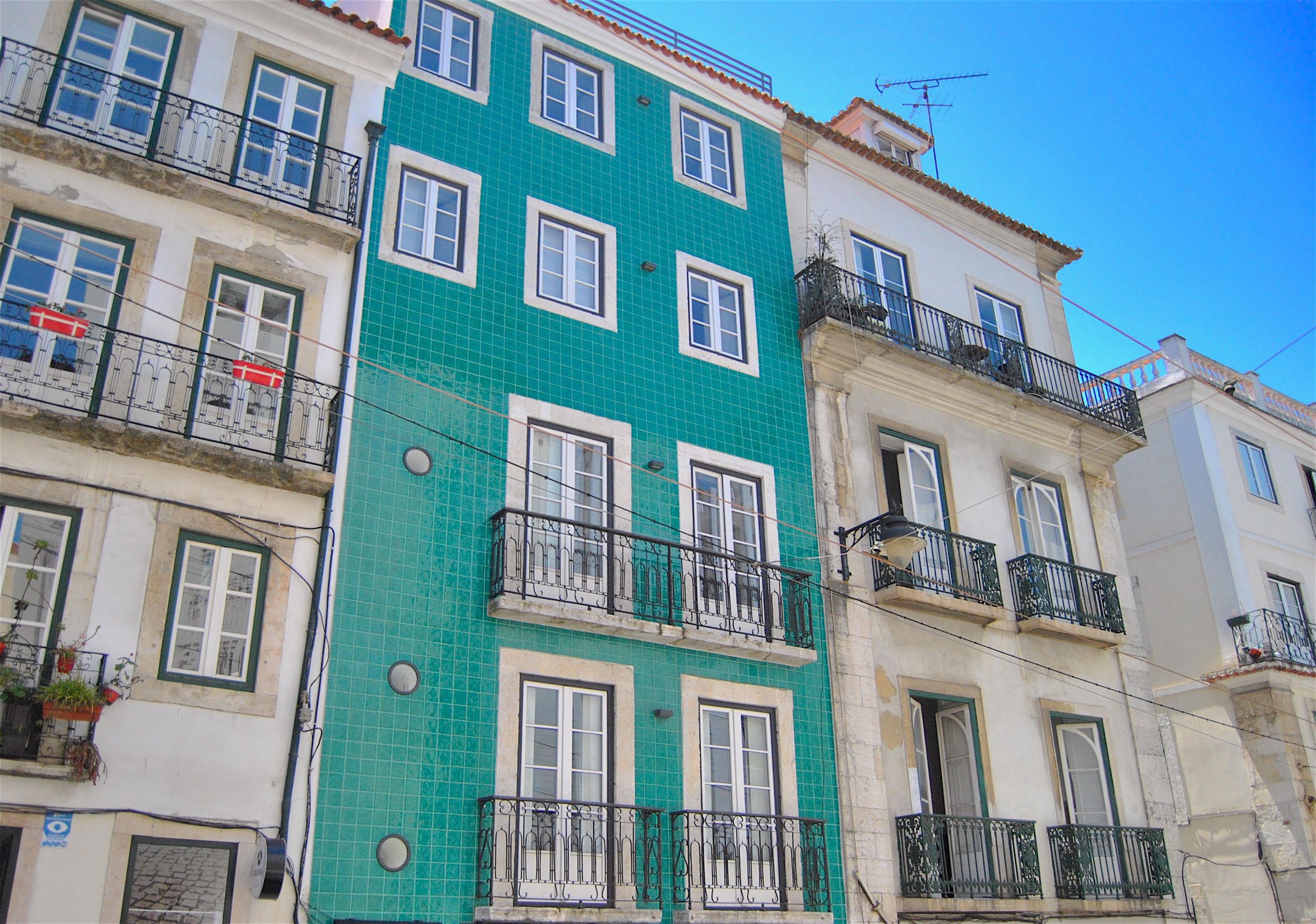 A multi-story building with balconies, a tiled facade, and a clear blue sky.