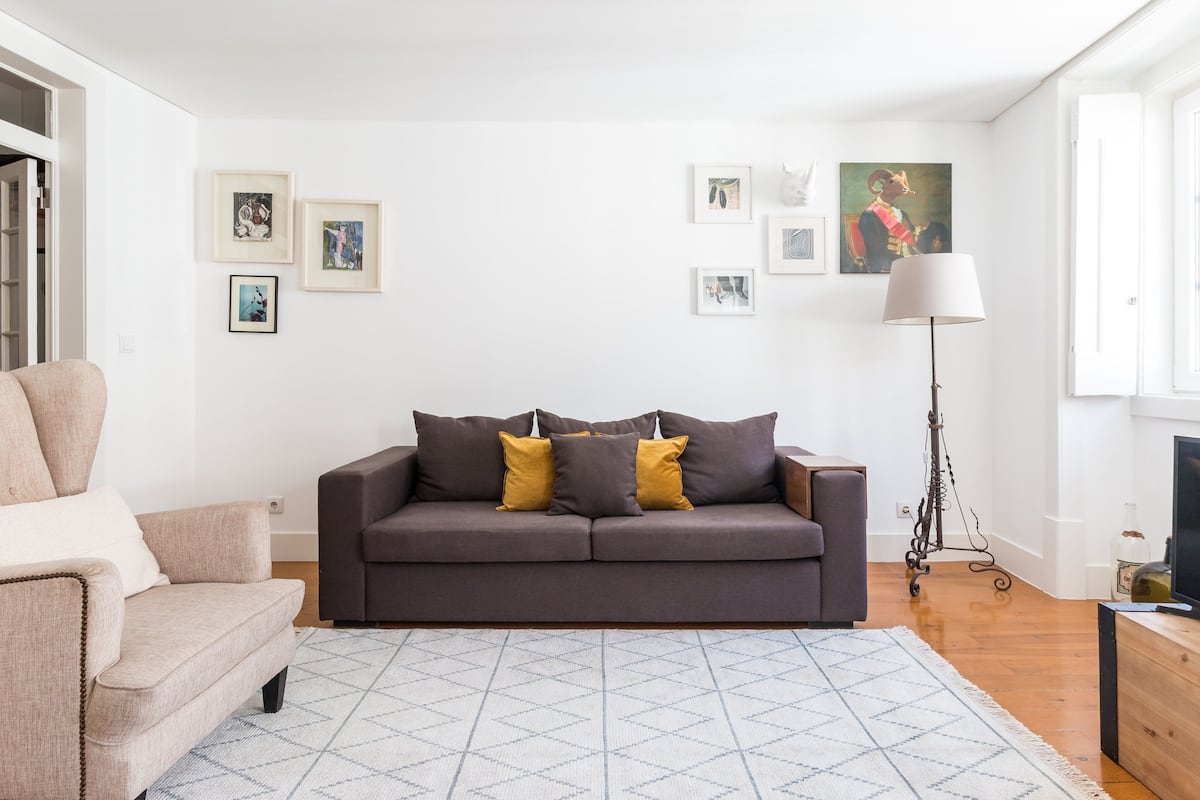 A modern living room with a grey sofa, a beige armchair, and a patterned rug.