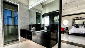 Un baño moderno con un espejo grande, encimera negra y cabina de ducha de vidrio.