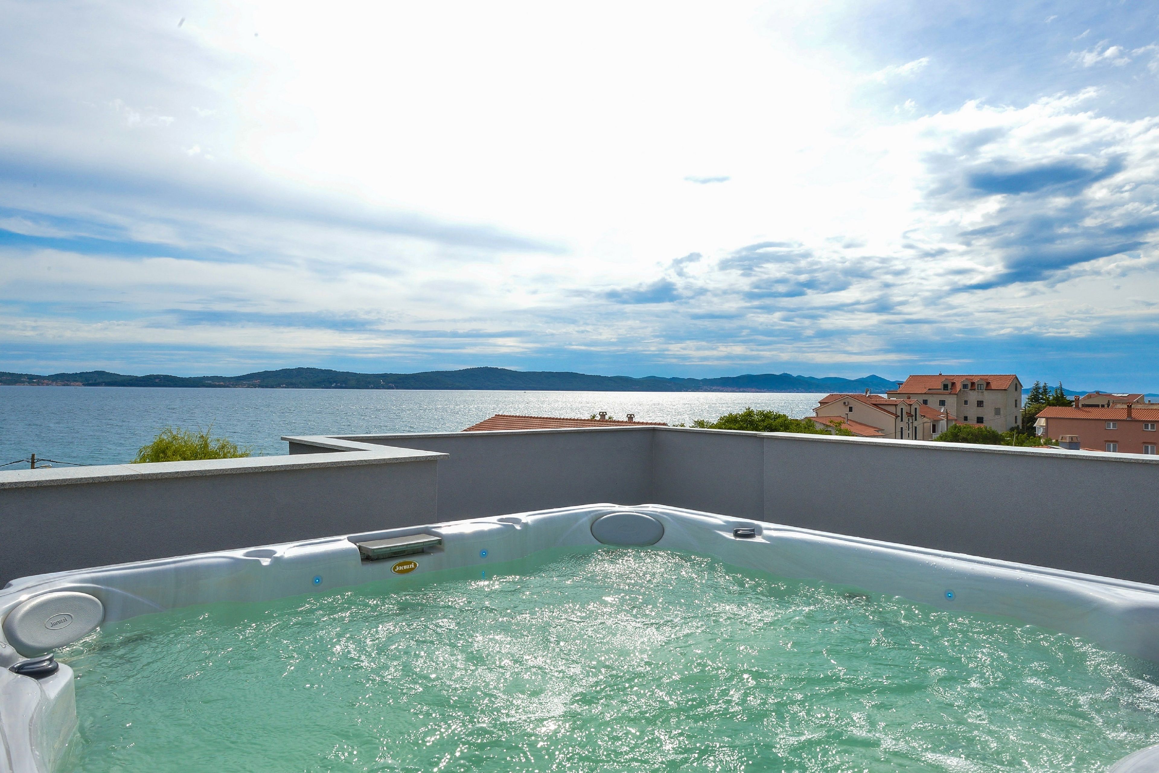 A hot tub with a view of the sea and mountains.