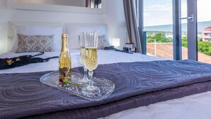A hotel room with a bed, a bottle of champagne, and two champagne flutes on a tray. - Sun Resort Nikolina (Bibinje)