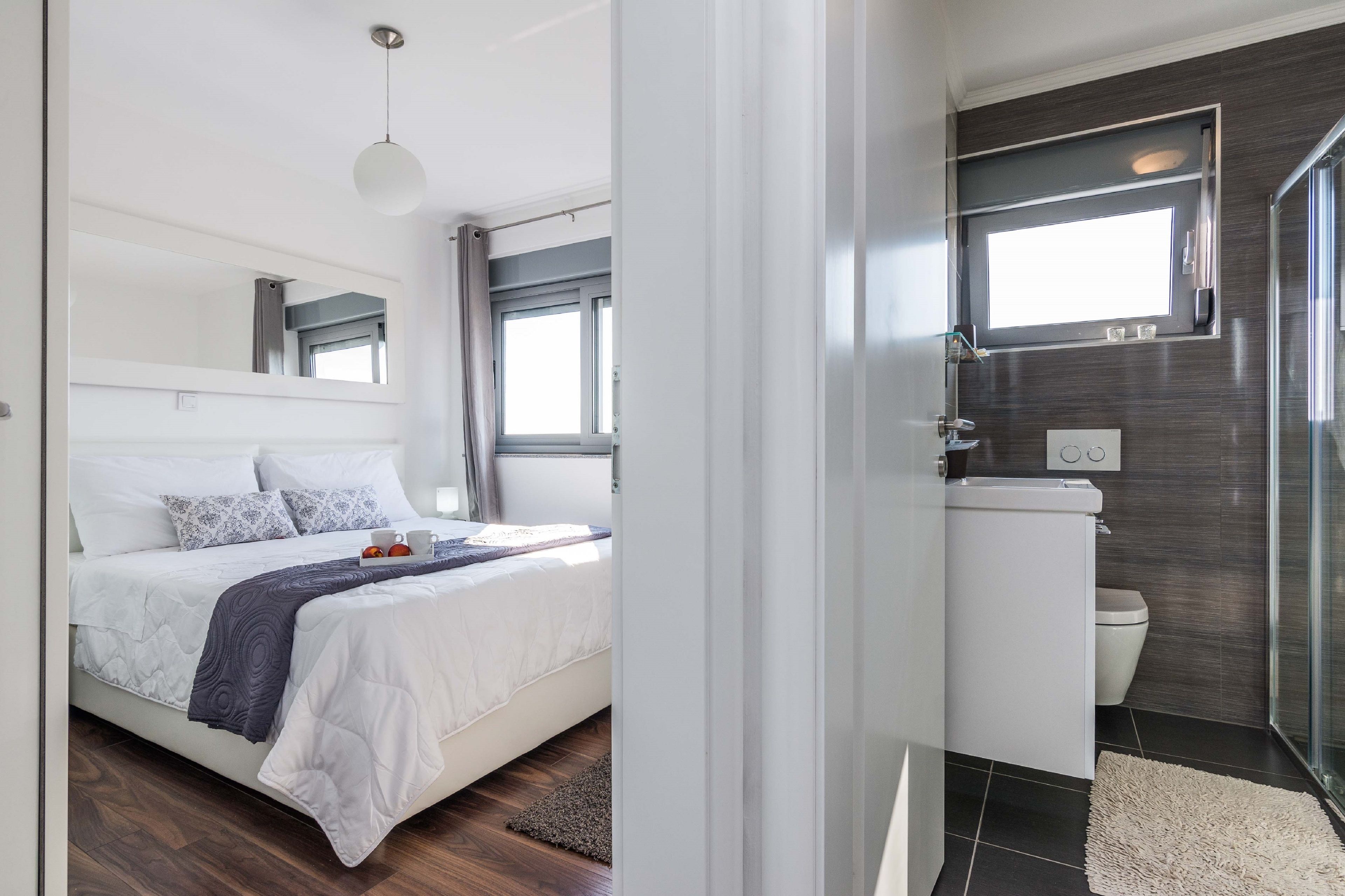 A modern bedroom with a large bed, a bedside table, and a window.