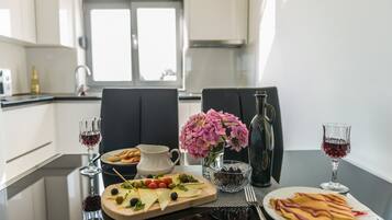 A dining table with a variety of food items, including a cheese board, a plate of crepes, and a pitcher of water.
