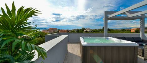 A rooftop terrace with a hot tub, outdoor seating, and a view of the cityscape.