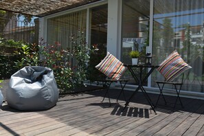 A wooden deck with a bean bag, two striped chairs, and a small table with a potted plant. - bnapartments Carregal (Porto)