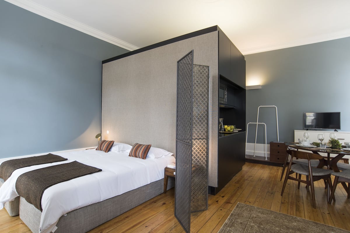Una habitación de hotel moderna con una cama grande, un comedor y un televisor.