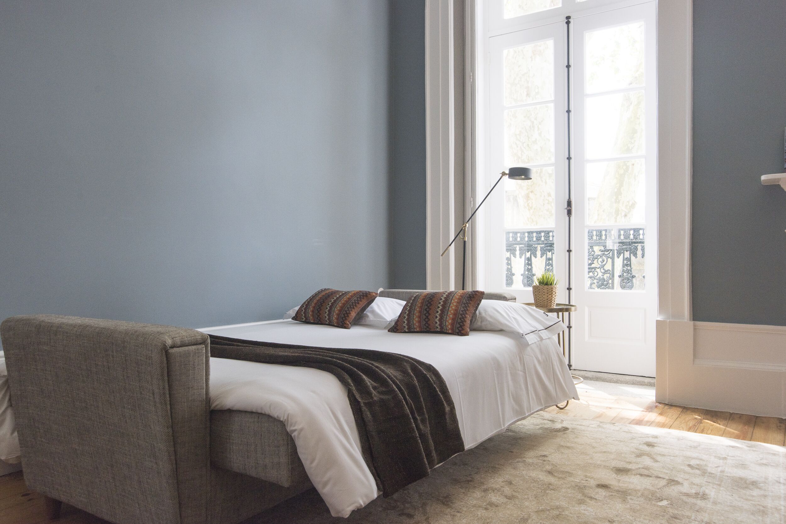 Une chambre à coucher avec un lit, une chaise, une lampe et une vue sur un balcon.