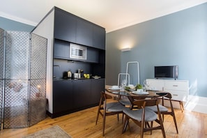 A modern kitchen with dark cabinetry, a microwave, and a dining area with a table set for four.