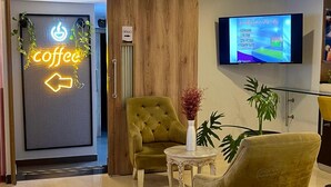 A modern lobby with a coffee sign, a television, and comfortable seating.