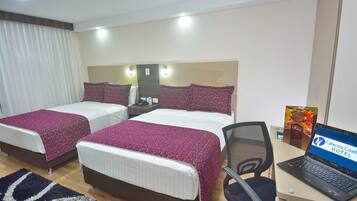 A hotel room with two beds, a desk with a laptop, and a chair.