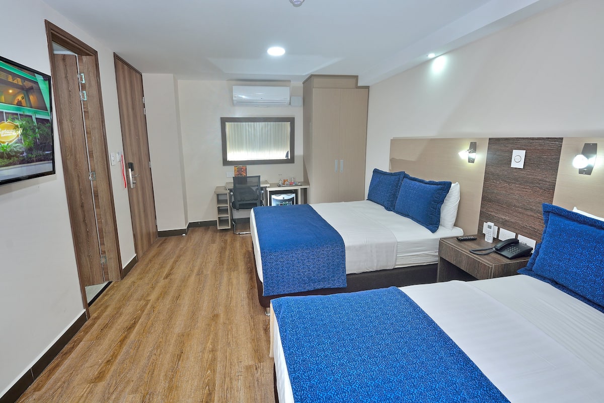 A hotel room with two beds, a desk, a chair, and a wardrobe.