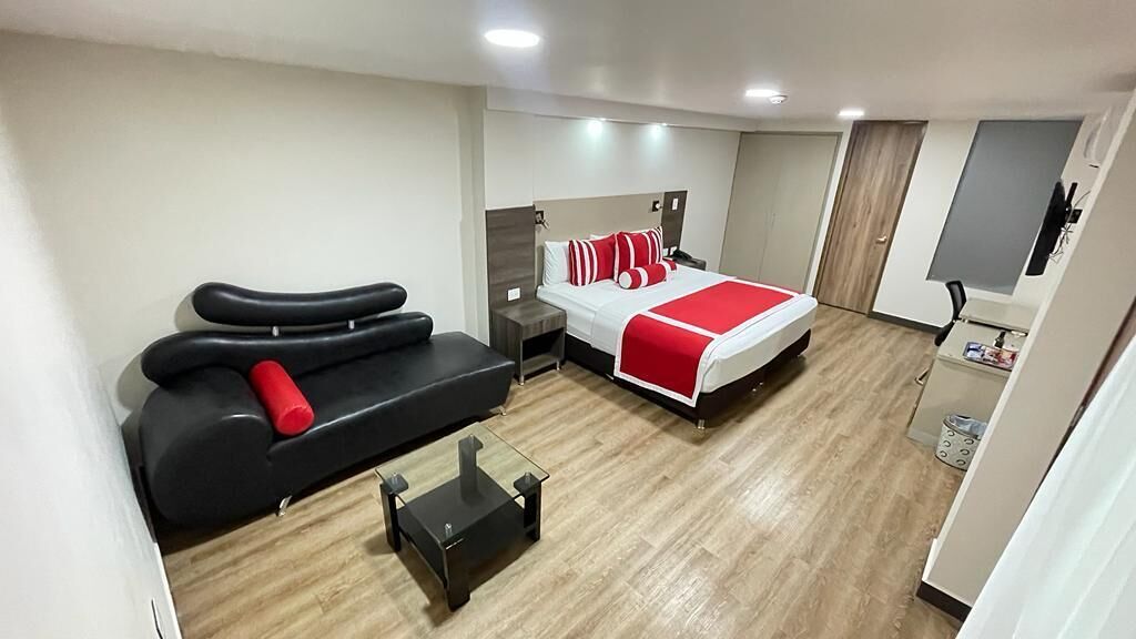 Una habitación de hotel moderna con una cama, un sofá, una mesita y un televisor.