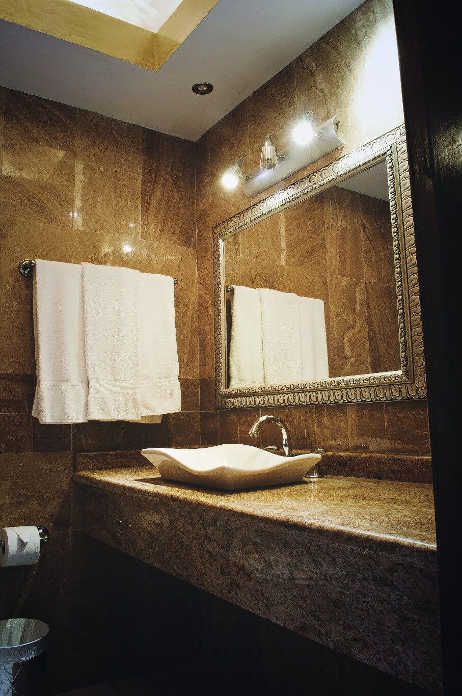 A bathroom with a marble sink, a large mirror, and two towels hanging on the wall.