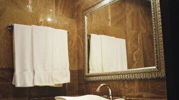 A bathroom with a marble sink, a large mirror, and two towels hanging on the wall.