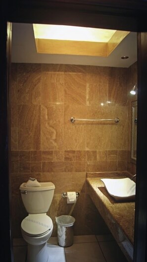 A bathroom with a toilet, a bidet, a trash can, and a sink.