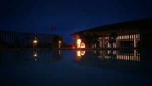 Vista nocturna de un edificio con una piscina que refleja su estructura.