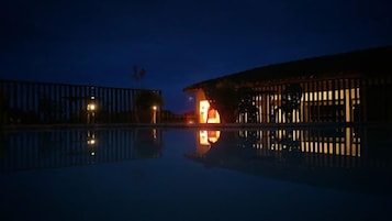 A nighttime view of a building with a pool reflecting its structure.