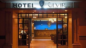 La entrada a un hotel con mostrador de recepción y una pared azul al fondo.