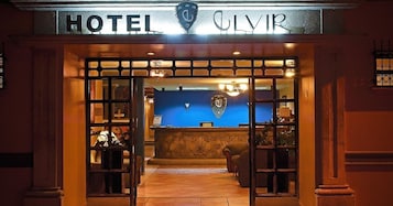 The entrance to a hotel with a reception desk and a blue wall in the background.