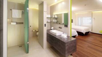 A modern bathroom with a shower, toilet, and sink, and a bedroom with a bed and window.