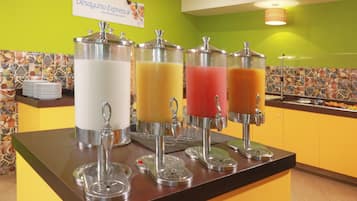 Una estación de bebidas con dispensadores para leche, jugo de naranja y otras dos opciones.