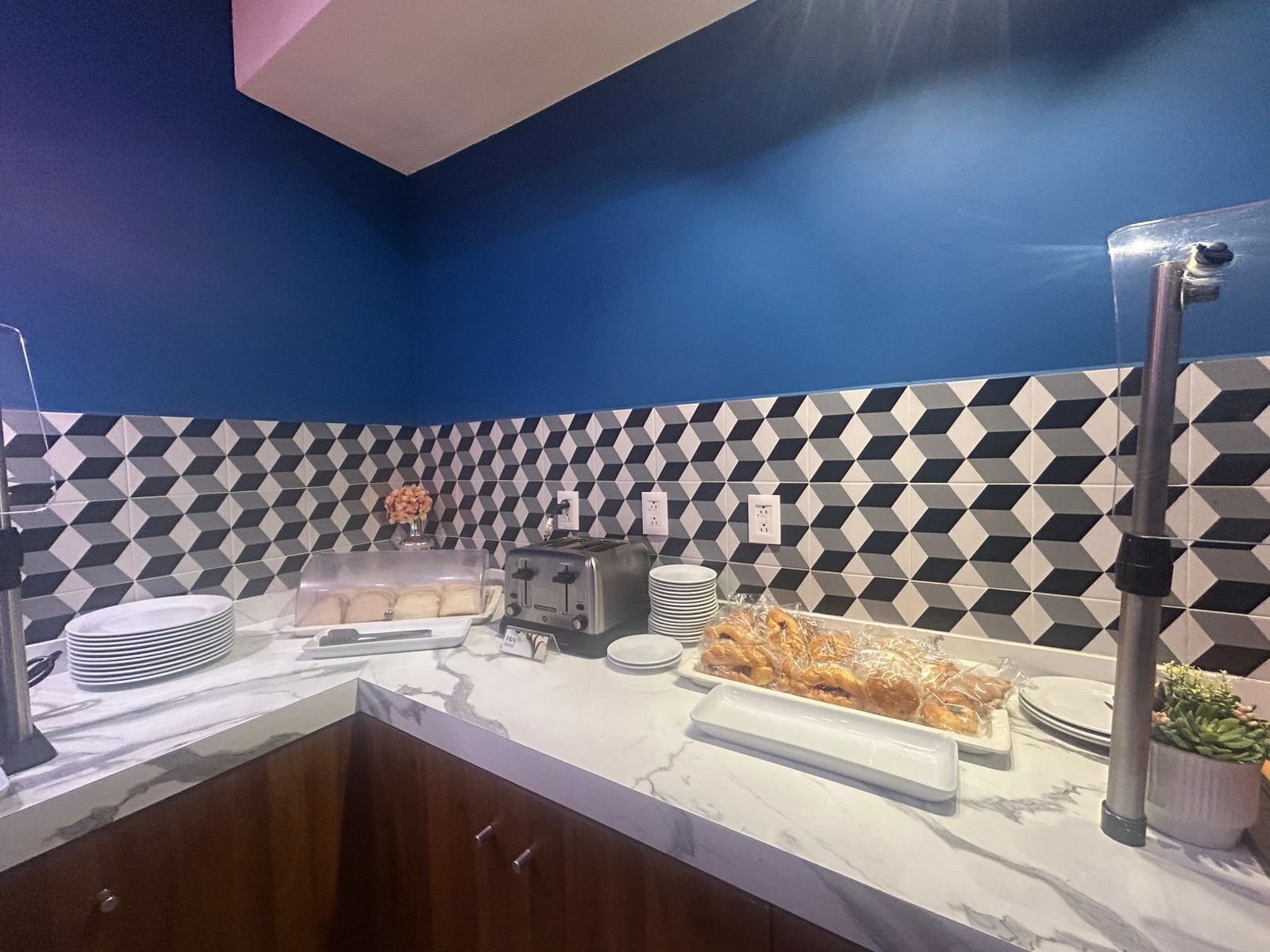 Mesa de desayuno tipo buffet con encimera de mármol, un tostador y una variedad de pasteles.