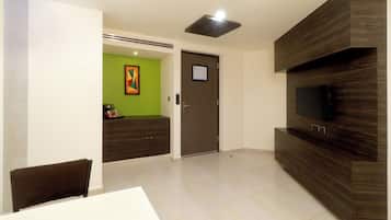 Una sala moderna con un televisor de pantalla plana montado en una pared de madera, una mesa de comedor con sillas y una pared de acento verde.