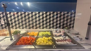 Un bufé con diferentes opciones de comida, entre ellas frutas, quesos y yogur.