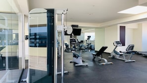 A modern gym with various exercise equipment, glass walls, and a clean, well-lit interior.