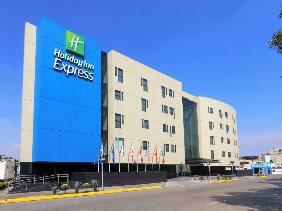 A Holiday Inn Express hotel with a prominent blue facade, multiple flags, and a modern architectural design.