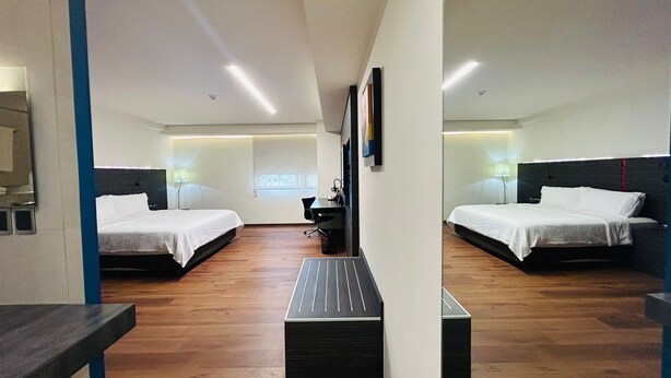 A hotel room with two beds, a desk, and a chair.