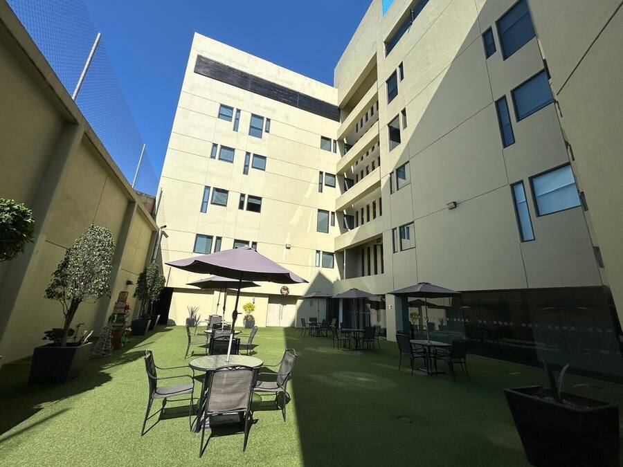 An outdoor courtyard with artificial grass, outdoor seating, and potted plants.
