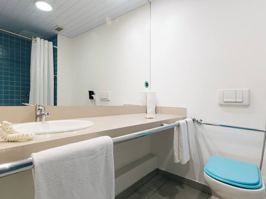 A bathroom with a white sink, a towel rack, a toilet, and a shower area.