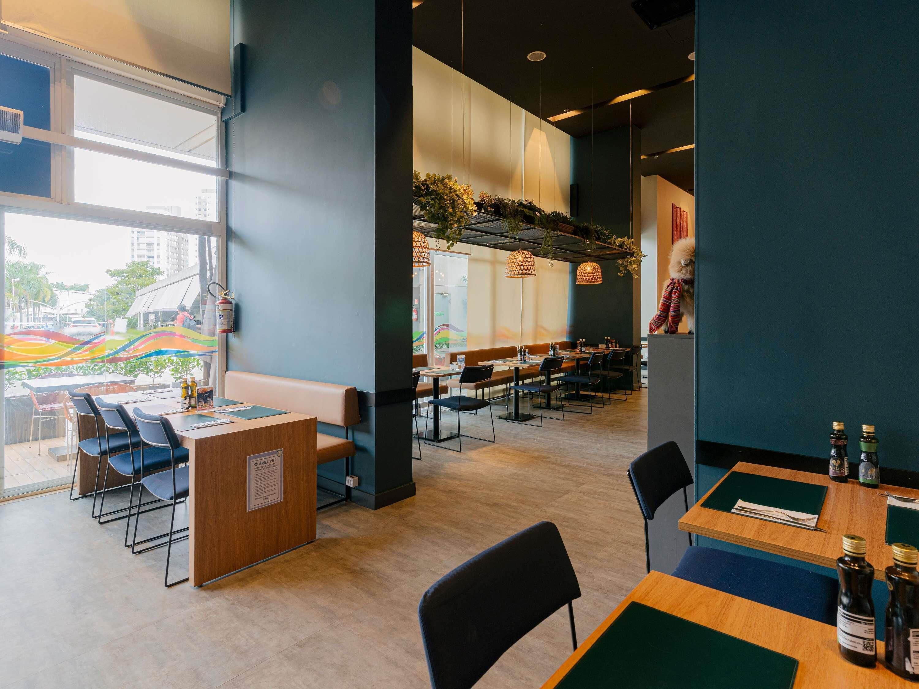 A modern restaurant interior with a counter, seating, and a view of the street.