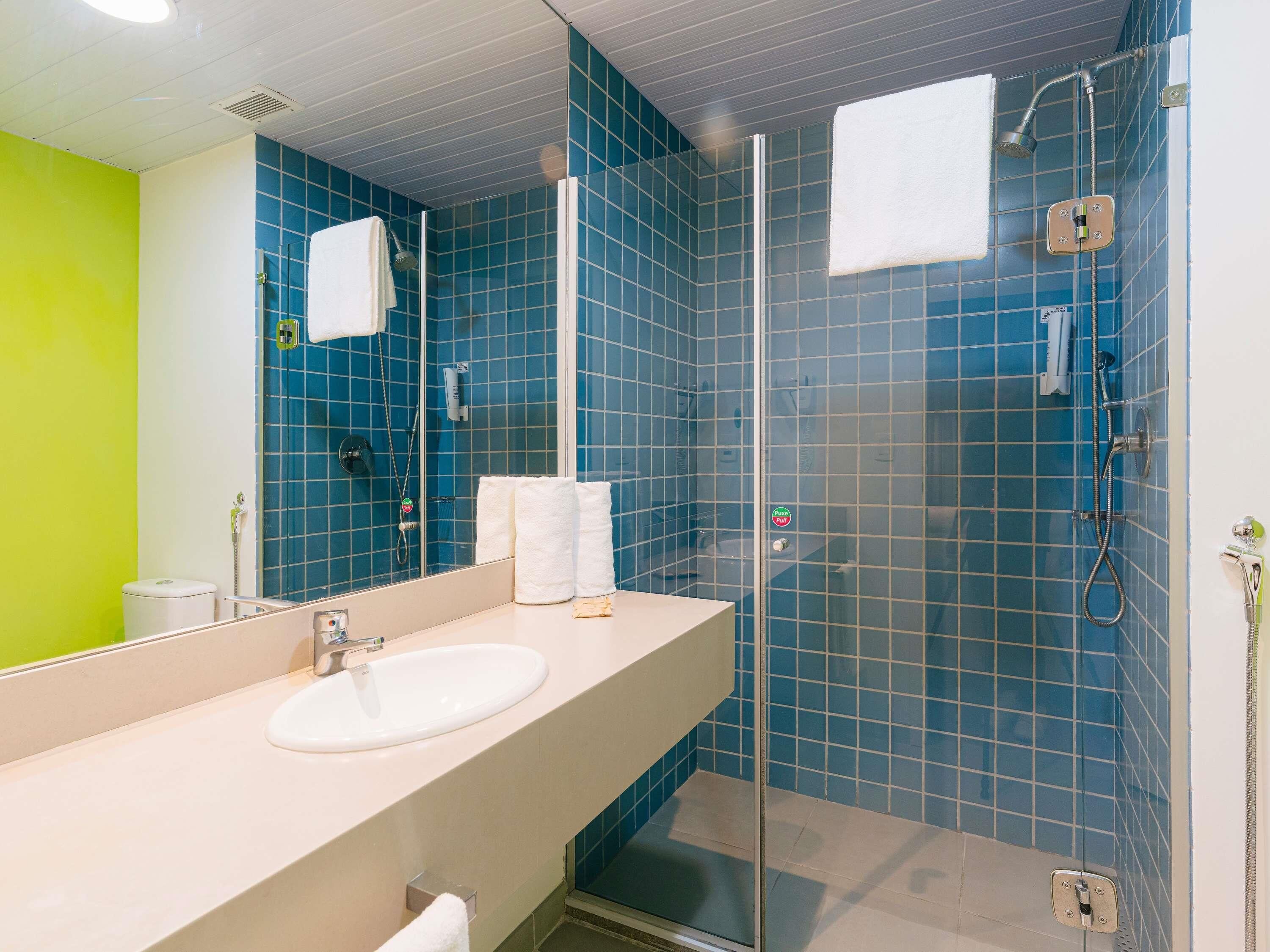Ein Badezimmer mit Duschkabine, Waschbecken und Spiegel.