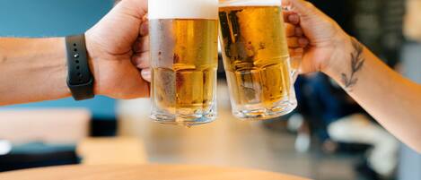 Due persone che brindano con delle birre al bancone di un bar.